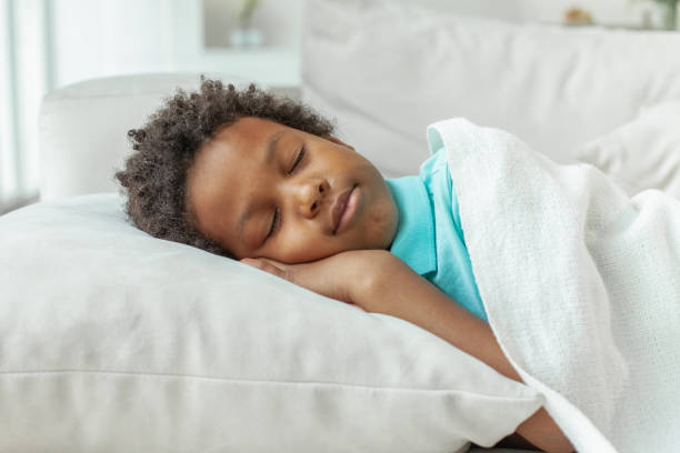 Cute little African American boy child sleeping in bed